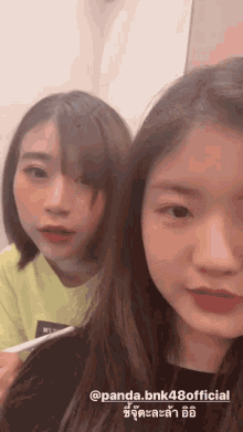 two girls are standing next to each other and one of them is holding a pen in her hand .