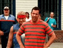 a man wearing a red and black striped shirt is standing in front of a group of people