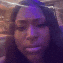 a close up of a woman 's face with purple lights in the background .