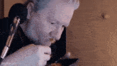a man is eating food in front of a microphone while holding a plate of food .