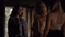 three women standing next to each other with one wearing a white tank top