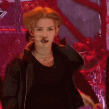 a man with a microphone in his mouth is wearing a black shirt and a leather jacket