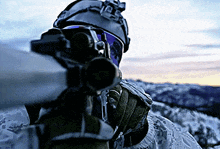 a close up of a person holding a rifle with a helmet and goggles on