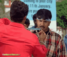 a man in a red shirt holds a knife to another man