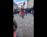 a woman in a red dress is holding a sword in front of a crowd of people