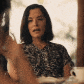 a woman is sitting at a table talking to another woman