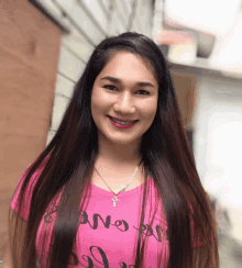 a woman wearing a pink shirt that says ano on it smiles for the camera