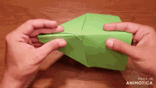 a person is holding a piece of green paper that says made in animatica