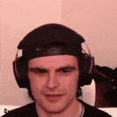 a man wearing headphones and a baseball cap is smiling .