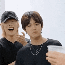 two young men are laughing and one is holding a cup