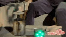 a person is sitting on a stool next to a coffee pot and a green light .