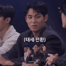 a group of young men are sitting around a table and one of them is wearing a jacket that says ' teen ' on the front