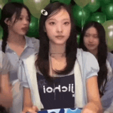 a girl is standing in front of a bunch of balloons and holding a gift box .