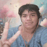a person giving a peace sign in front of a painting