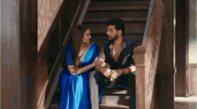 a man and woman are sitting on a set of stairs looking at each other .