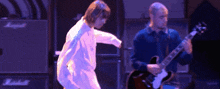 a man playing a guitar next to a man dancing on a stage