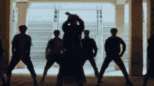 a group of men are standing in a room with their backs to the camera