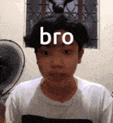 a young man is standing in front of a fan with the word bro on his face .