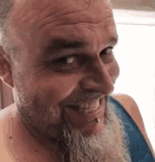 a man with a beard and piercings is smiling .