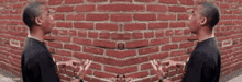 two men are standing in front of a red brick wall and talking to each other .