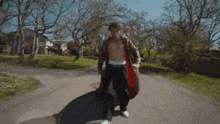 a shirtless man is walking down a street with trees in the background