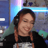 a woman wearing headphones and a shirt that says motto motto is smiling