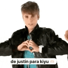 justin bieber is making a heart with his hands .