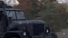 a military vehicle is driving down a street with the walking dead 7 written on the bottom