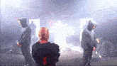 a group of people in black hoodies are standing in a room