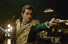 a man in a green and gold military uniform holds a sword