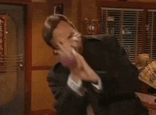 a man in a suit is dancing in a room with blinds on the windows .