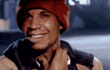 a man wearing a red beanie is smiling and adjusting his jacket