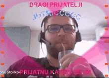 a man wearing glasses and a headset is drinking through a straw