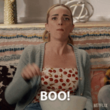 a woman sitting on a couch with a netflix logo on the bottom right