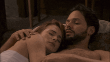 a man and a woman are laying on a bed together