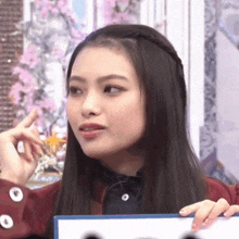 a woman with long black hair is holding a piece of paper and making a face