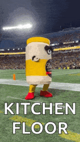 a jar of mustard mascot is standing on a football field .