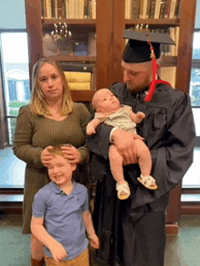 a man in a graduation cap and gown holds a baby in his arms