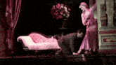 a woman in a pink dress is kneeling down next to a man in a suit on a stage .