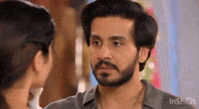 a man with a beard is looking at a woman with a necklace .