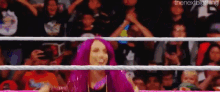 a woman with purple hair is standing in a wrestling ring .