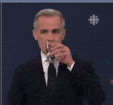 a man in a suit and tie holds a glass of water
