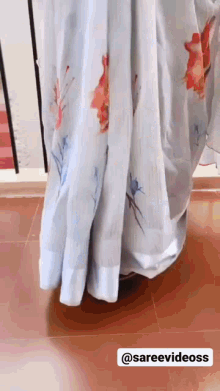 a woman is wearing a light blue floral printed saree