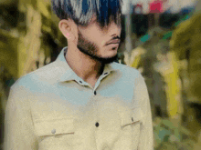 a man with blue hair and a beard is wearing a tan shirt