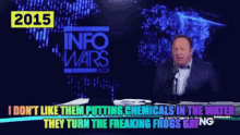 a man is talking into a microphone in front of a screen that says 2015 info wars
