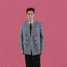 a man in a suit and tie with his arms outstretched against a pink background