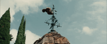 a weather vane on top of a wooden roof with the letter e visible