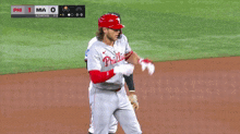 a baseball player wearing a phillies jersey stands on a field