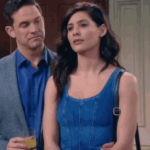 a man and a woman are standing next to each other and the woman is wearing a blue tank top