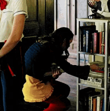 a woman is kneeling down in front of a bookshelf with a book titled " a brief history "